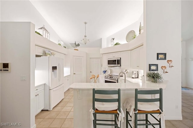 597 Lambton Ln, Naples, FL 34104 - kitchen with stainless steel appliances, a peninsula, backsplash, light countertops, and high vaulted ceiling