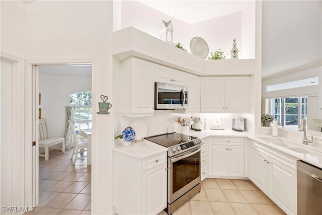 597 Lambton Ln, Naples, FL 34104 - kitchen with stainless steel appliances, a sink, white cabinetry, and light tile patterned floors