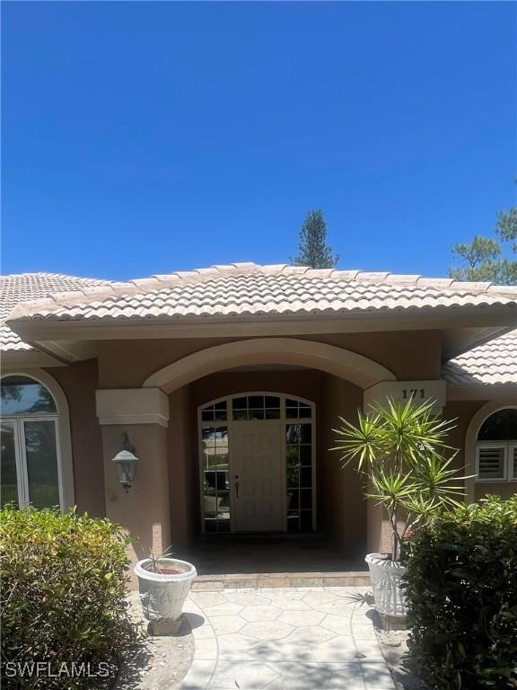 view of exterior entry featuring a tile roof and stucco siding