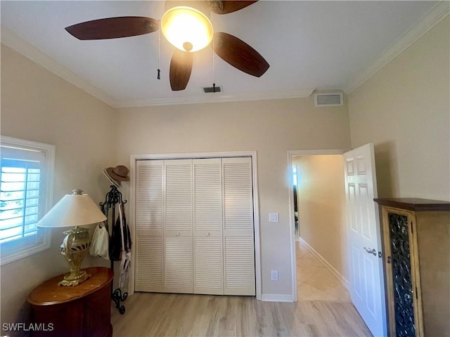 bedroom featuring light wood finished floors, visible vents, ornamental molding, a closet, and ceiling fan