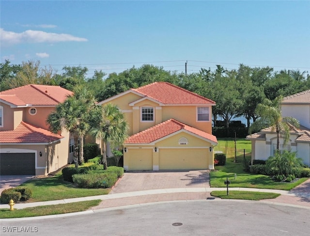 mediterranean / spanish-style house featuring stucco siding, a tile roof, decorative driveway, and a front lawn