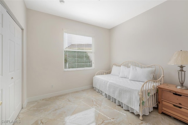 bedroom with baseboards, marble finish floor, and a closet