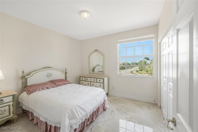 bedroom featuring baseboards, marble finish floor, and a closet