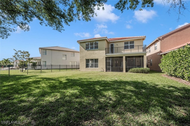 rear view of property featuring a tiled roof, fence, a yard, stucco siding, and a sunroom