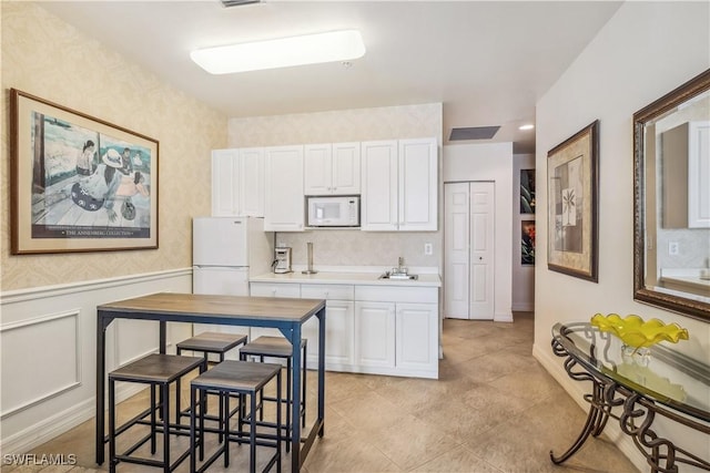 2797 1st St Unit 2003, Fort Myers, FL 33916 - kitchen with visible vents, wallpapered walls, white appliances, and white cabinetry