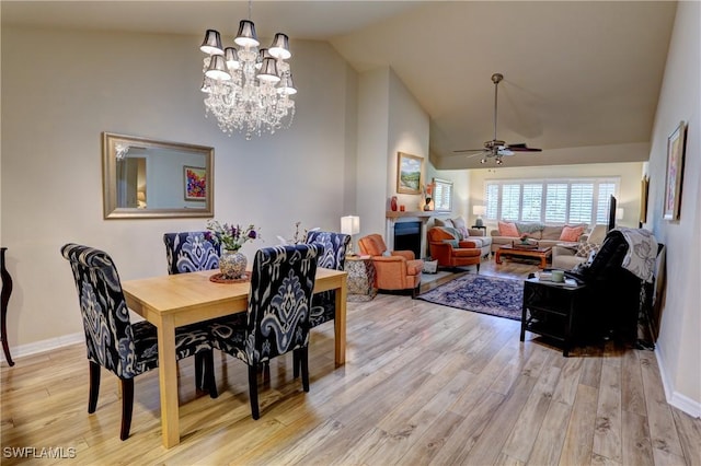 dining room featuring high vaulted ceiling, baseboards, light wood finished floors, and ceiling fan with notable chandelier
