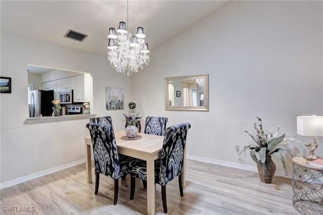 dining room featuring a chandelier, vaulted ceiling, visible vents, and light wood finished floors