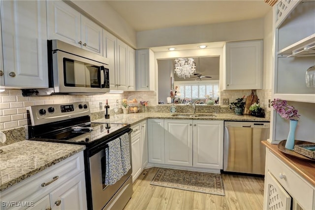 kitchen featuring a sink, an inviting chandelier, white cabinetry, light wood-style flooring, and appliances with stainless steel finishes