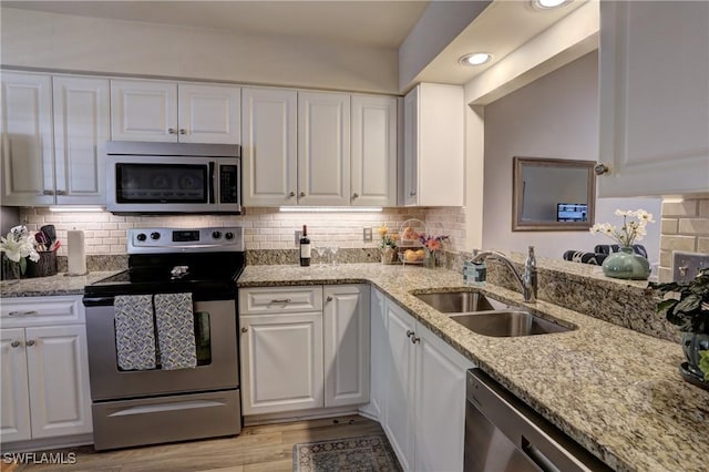 kitchen with white cabinets, light wood-style flooring, appliances with stainless steel finishes, and a sink