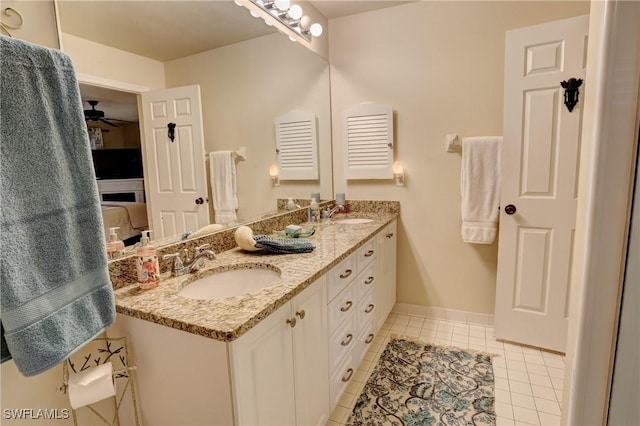 ensuite bathroom with double vanity, tile patterned flooring, baseboards, and a sink