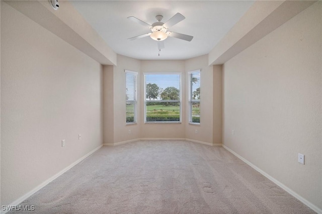 empty room featuring baseboards, a ceiling fan, and light colored carpet