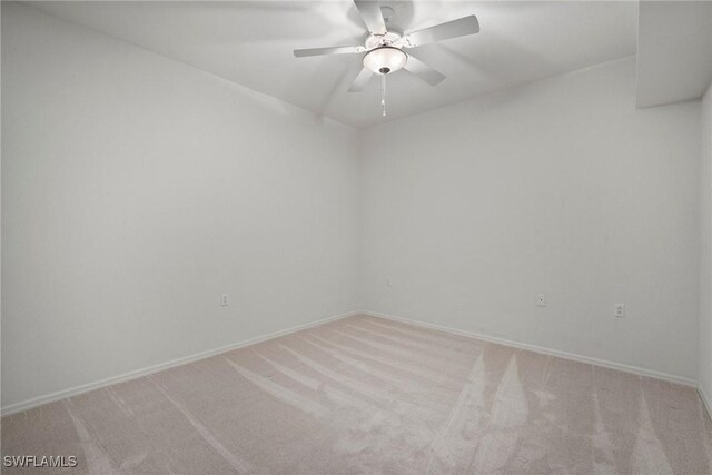 carpeted empty room featuring ceiling fan and baseboards