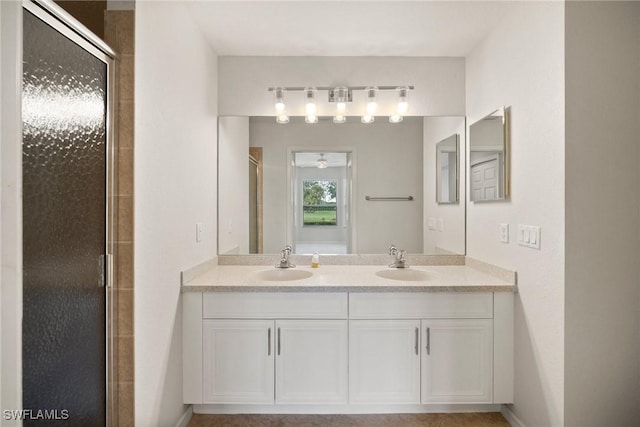 full bathroom with double vanity, a shower stall, and a sink