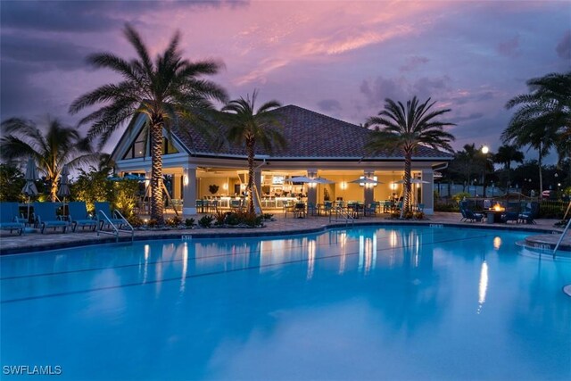 community pool with an outdoor fire pit and a patio