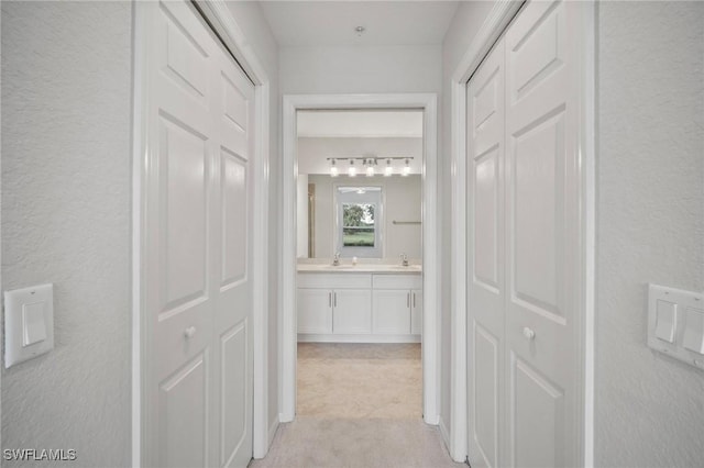 hall with a textured wall and a sink