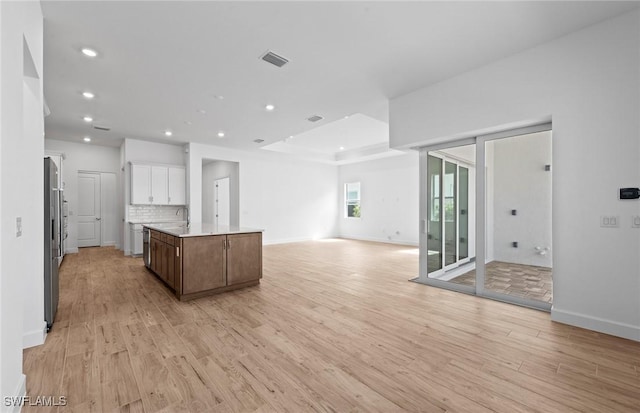 kitchen featuring visible vents, open floor plan, an island with sink, recessed lighting, and light wood finished floors