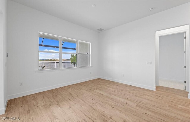 unfurnished room with baseboards, light wood finished floors, and visible vents