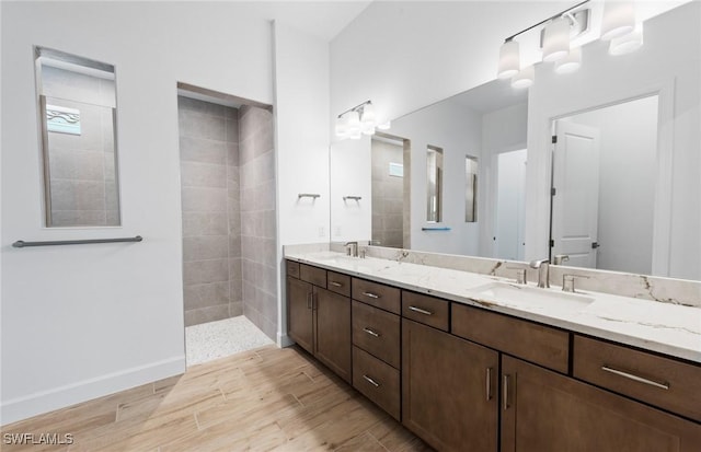 bathroom featuring double vanity, a sink, walk in shower, and wood finished floors