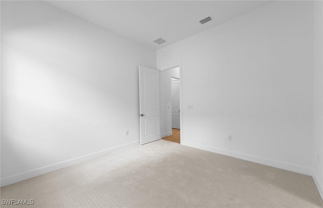 spare room with visible vents, baseboards, and light colored carpet
