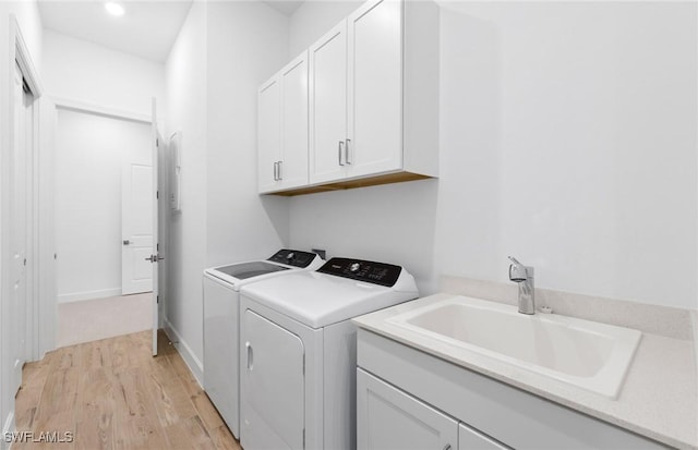 laundry area with light wood-style floors, recessed lighting, washing machine and clothes dryer, a sink, and cabinet space