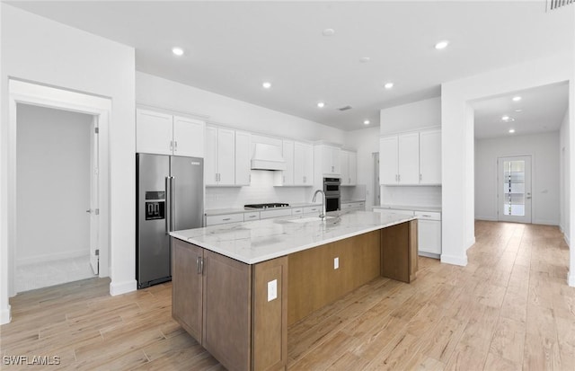 kitchen featuring premium range hood, stainless steel appliances, light wood-style flooring, and white cabinetry