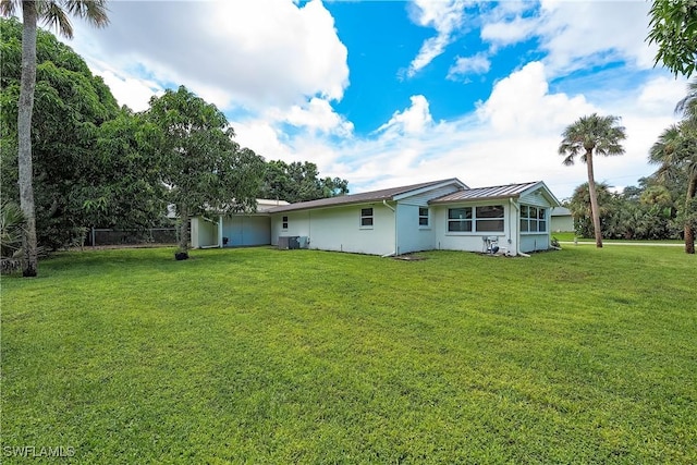 27525 Michigan St, Bonita Springs, FL 34135 - rear view of property with fence, central AC, stucco siding, a standing seam roof, and a lawn