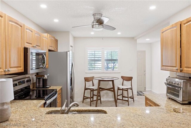 733 Landover Ct Unit 203, Naples, FL 34104 - kitchen with stainless steel appliances, a ceiling fan, a sink, and light stone counters