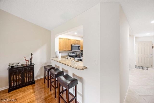 733 Landover Ct Unit 203, Naples, FL 34104 - kitchen featuring light brown cabinets, a breakfast bar area, stainless steel appliances, baseboards, and recessed lighting