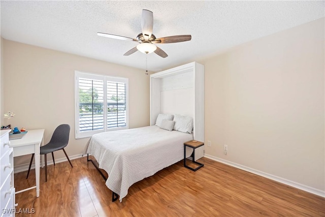 733 Landover Ct Unit 203, Naples, FL 34104 - bedroom featuring light wood-type flooring, a ceiling fan, baseboards, and a textured ceiling