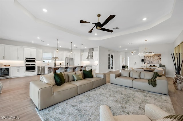 15766 Cortina St, Naples, FL 34114 - living room featuring wine cooler, recessed lighting, light wood-style floors, a ceiling fan, and a tray ceiling