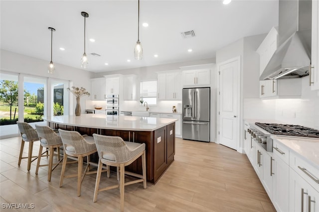 15766 Cortina St, Naples, FL 34114 - kitchen featuring stainless steel appliances, wall chimney exhaust hood, white cabinets, a large island, and recessed lighting