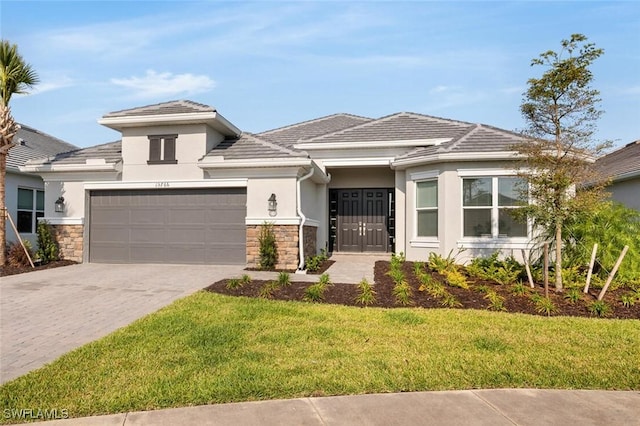 15766 Cortina St, Naples, FL 34114 - prairie-style home with stone siding, stucco siding, driveway, a front lawn, and a garage