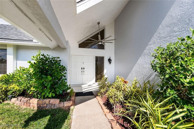 view of exterior entry featuring stucco siding and ceiling fan