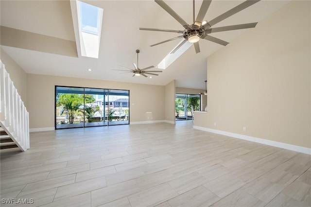 unfurnished living room with baseboards, a skylight, ceiling fan, and high vaulted ceiling
