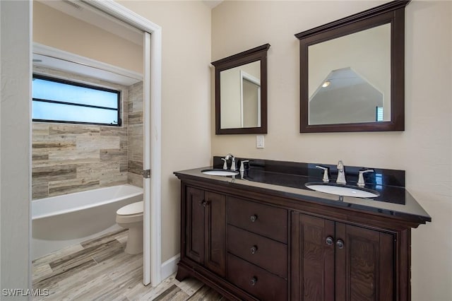 bathroom with a sink, toilet, double vanity, and wood finished floors