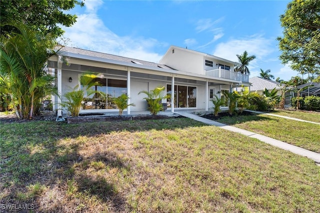 back of house with a lawn, stucco siding, and a balcony