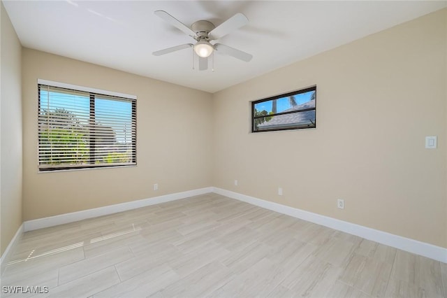 spare room with baseboards, ceiling fan, and light wood-type flooring