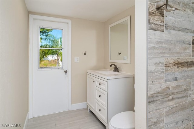 bathroom with baseboards, vanity, and toilet