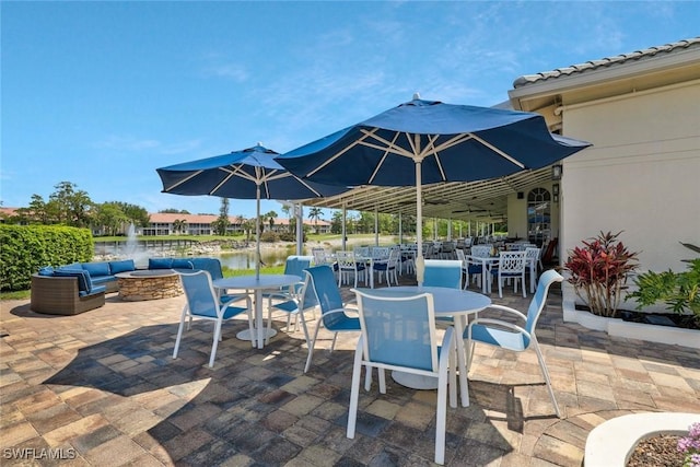 view of patio with a fire pit, a water view, and outdoor dining area