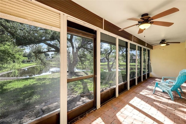 unfurnished sunroom with ceiling fan and a water view