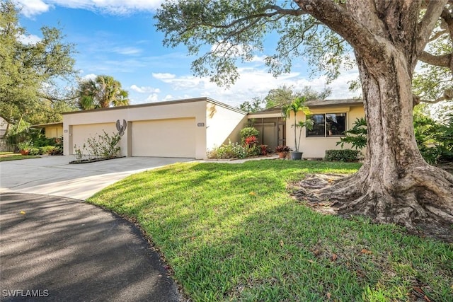 mid-century home with stucco siding, driveway, a front yard, and a garage