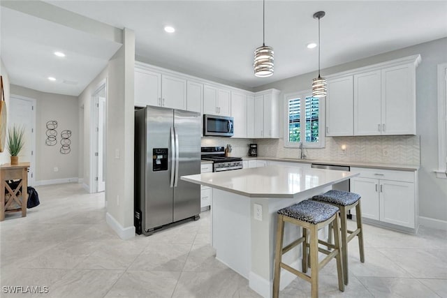 kitchen with white cabinets, stainless steel appliances, backsplash, light countertops, and a kitchen island