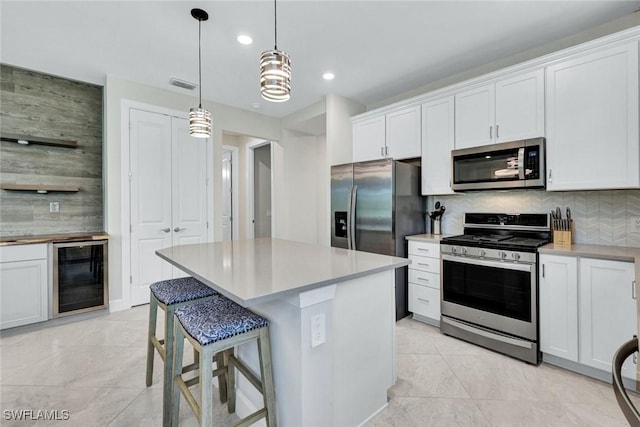 kitchen featuring visible vents, white cabinetry, backsplash, beverage cooler, and appliances with stainless steel finishes