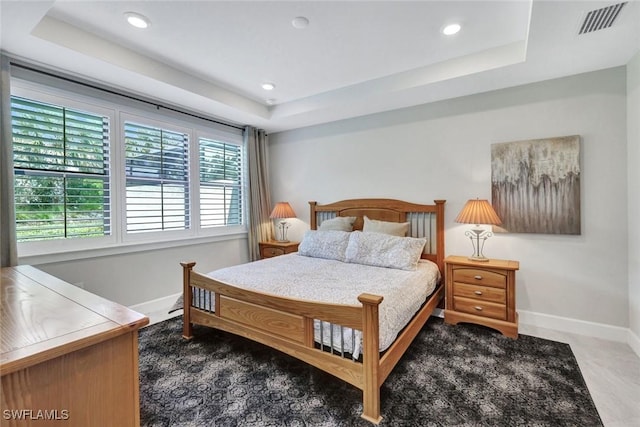 bedroom with a raised ceiling, visible vents, and baseboards