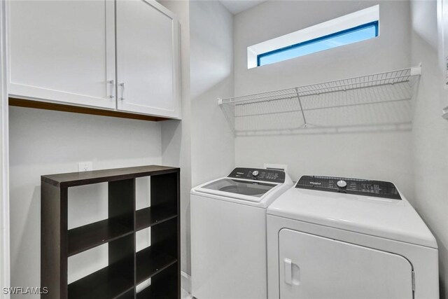 laundry room with washing machine and clothes dryer and cabinet space