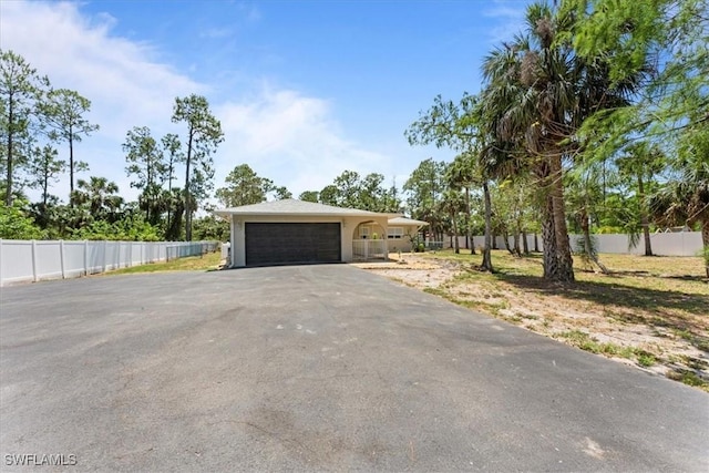 view of front of house with asphalt driveway, a garage, and fence