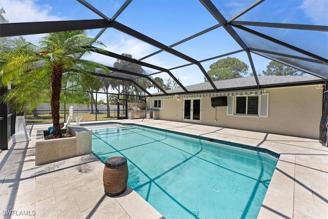 swimming pool featuring a patio area, glass enclosure, and french doors