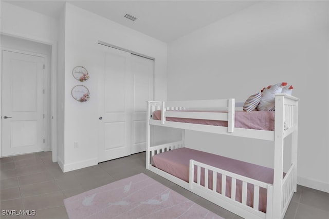 bedroom with baseboards, visible vents, tile patterned flooring, and a closet
