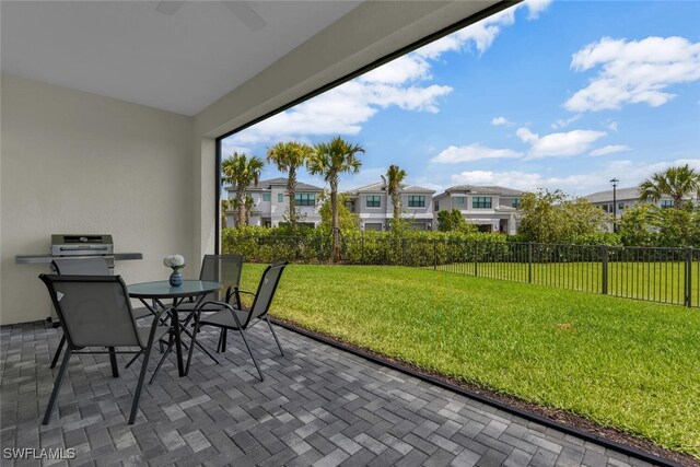 view of patio / terrace featuring a ceiling fan, fence, a residential view, and outdoor dining space