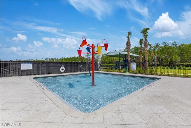 view of swimming pool featuring a water play area, fence, and playground community